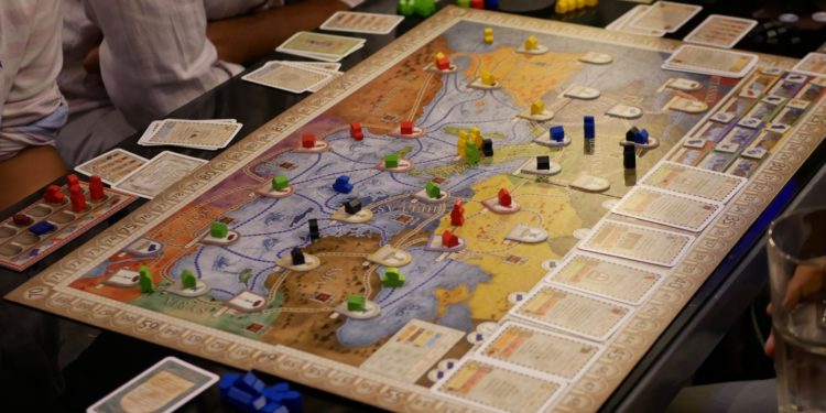 person in white shirt sitting beside table with puzzle game