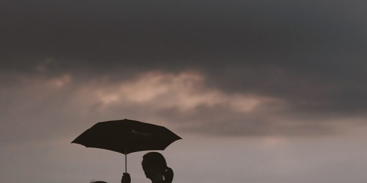 silhouette of woman holding umbrella standing in front of girl on hill during night time