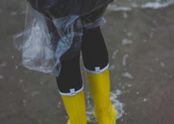 Person Wearing Clear Plastic Raincoat and Pair of Yellow Rainboots