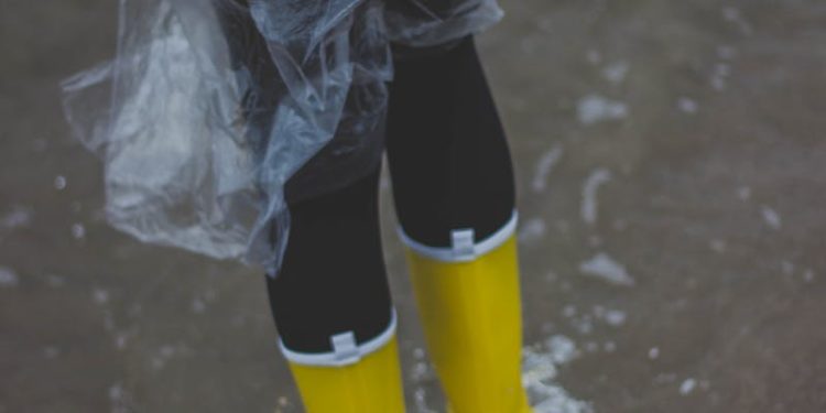 Person Wearing Clear Plastic Raincoat and Pair of Yellow Rainboots